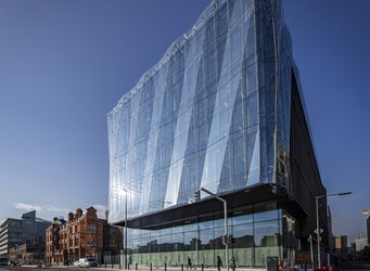 Zeigt den Salesforce Tower in Dublin, der bläulich in der Sonne schimmert. 
